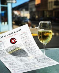 A glass filled with drink kept on a paper of clear creek cidery